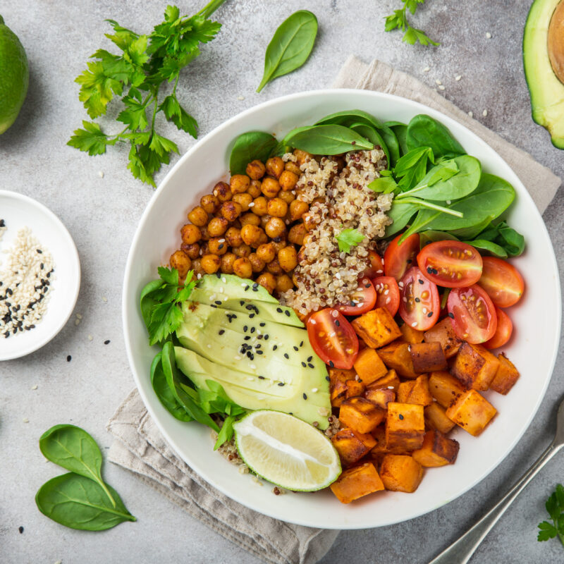 healhty vegan lunch bowl. Avocado, quinoa, sweet potato, tomato, spinach and chickpeas vegetables salad.
